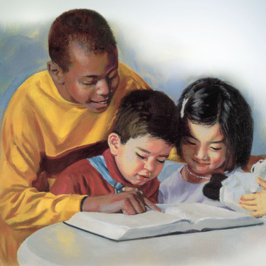 An older boy reads the Bible to two small children