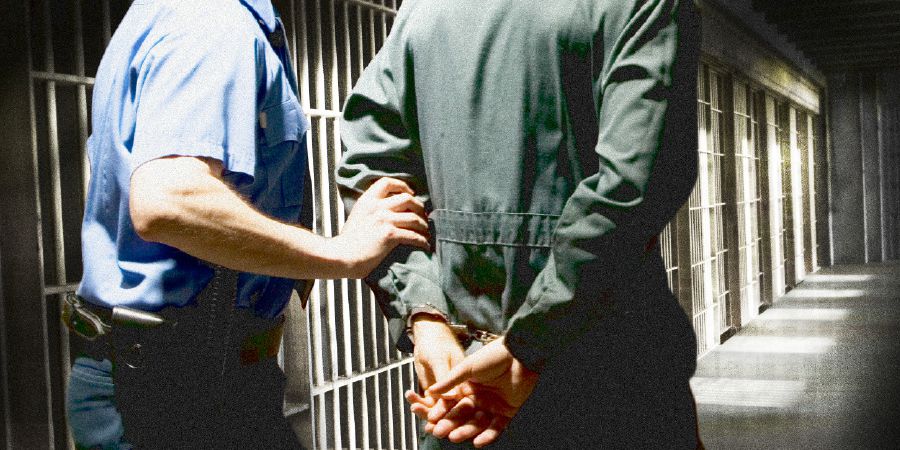 A handcuffed brother is led in prison by a guard