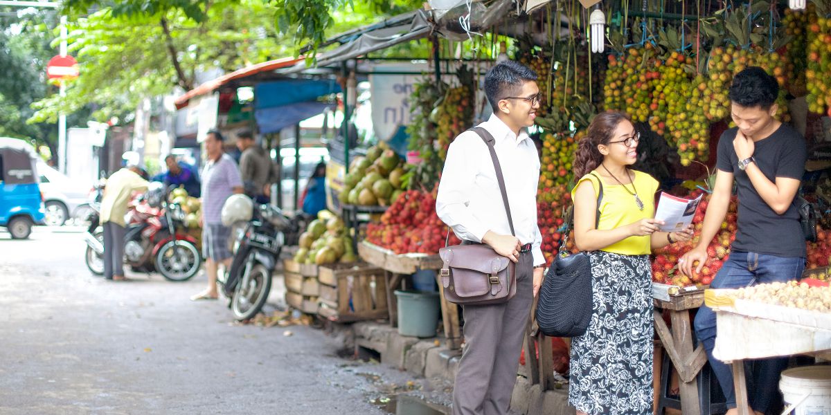 Two of Jehovah’s Witnesses preach in a marketplace in Indonesia
