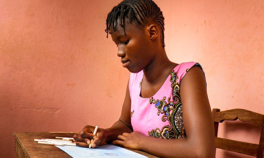 Aminata, a 15-year-old student in Guinea-Bissau, draws a picture of Paradise