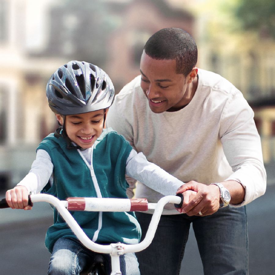 A father teaches his son to ride a bicycle
