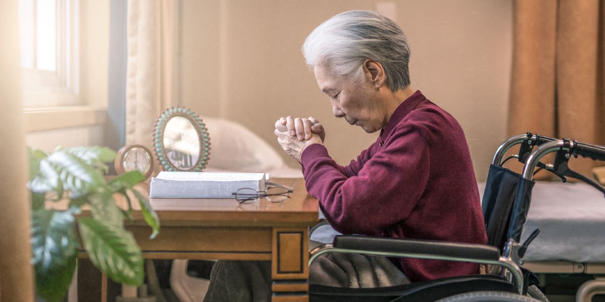 An older wheelchair-bound sister prays