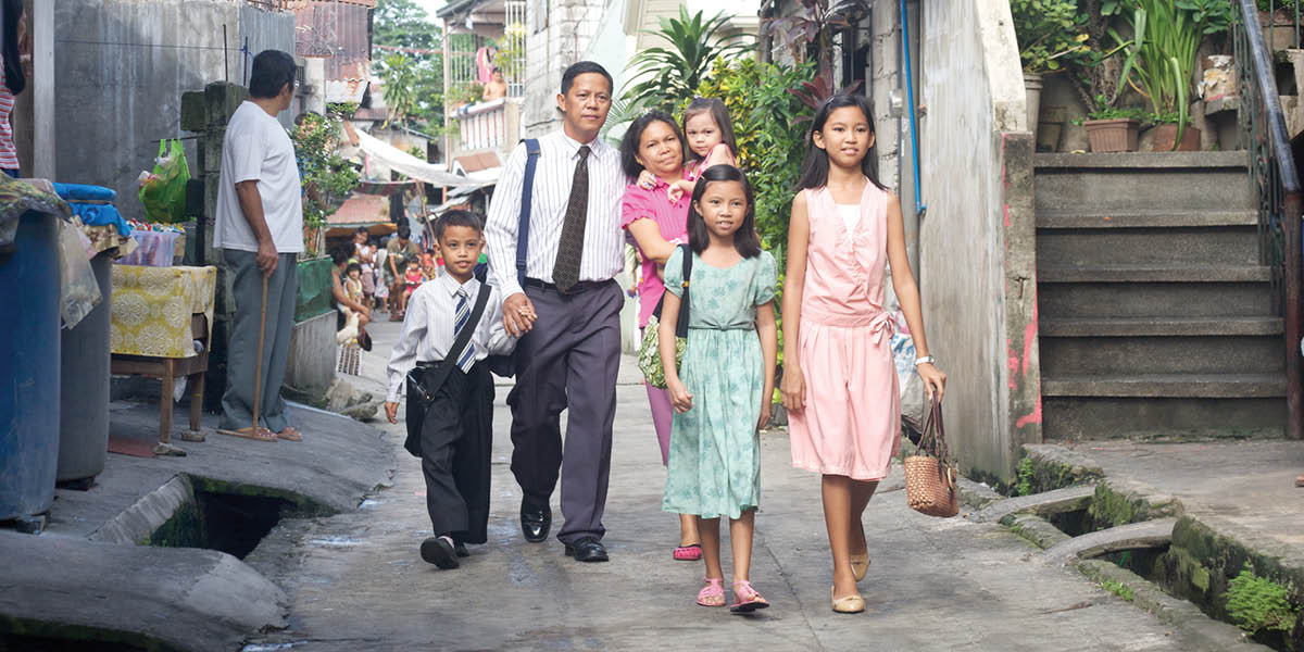 A family of six with limited means walking through a poor neighborhood to meet their brothers for spiritual activities.