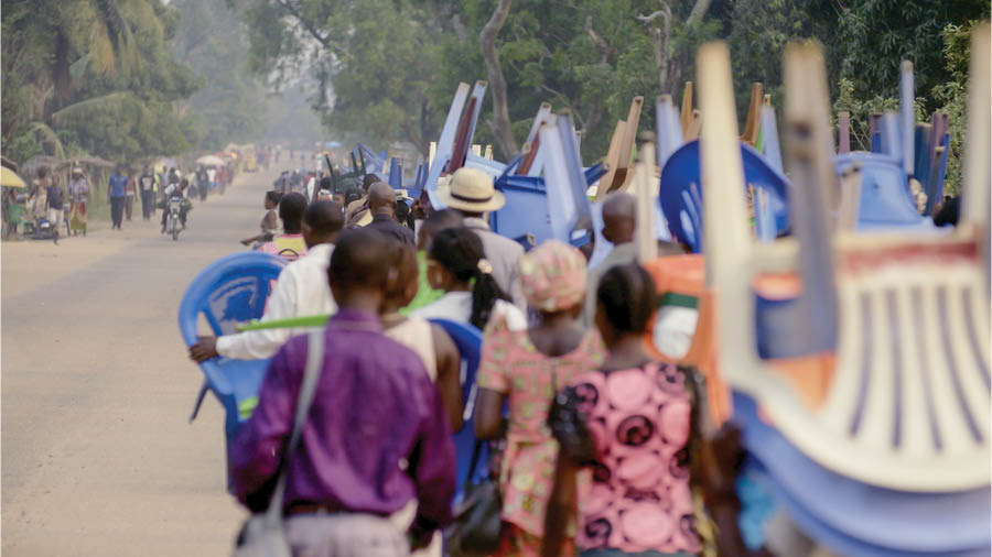 A scene from the video ‘Love Never Fails Despite . . . Poverty—Congo.’ A large crowd of brothers and sisters walk to a convention location. Many carry chairs and other personal belongings.