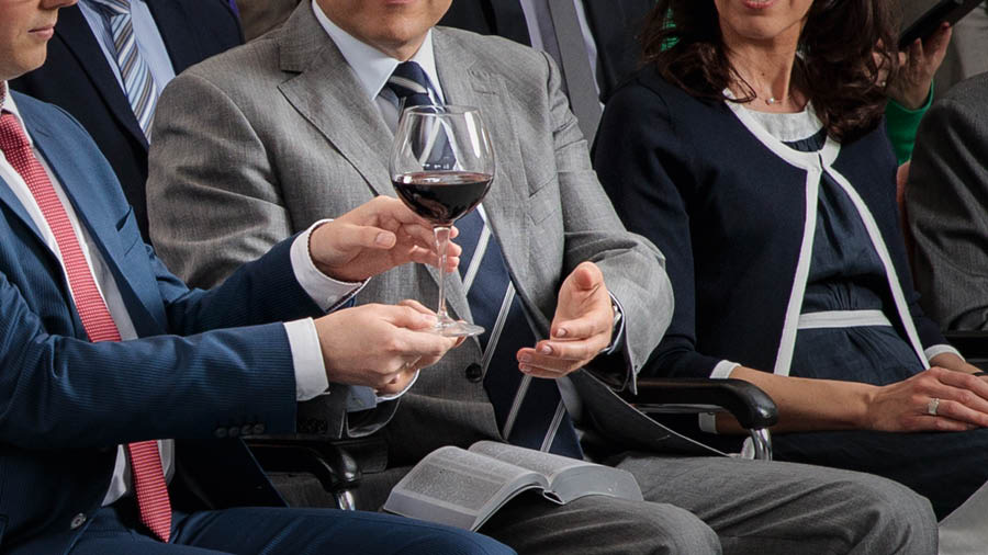 A brother passing a glass of wine to another brother during the Memorial.