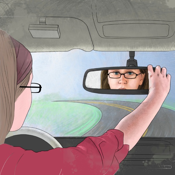 A girl driving a car and looking at herself in the rearview mirror