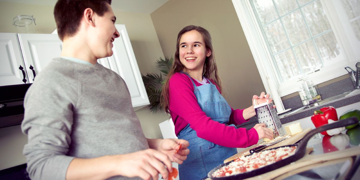 A brother and sister make a pizza together