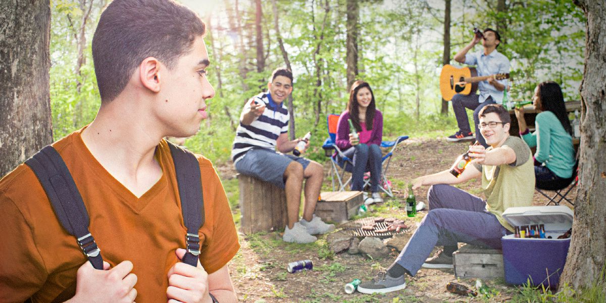 A young man is offered alcohol at a picnic