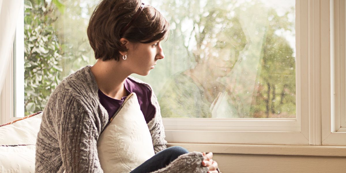 A depressed girl stares out a window