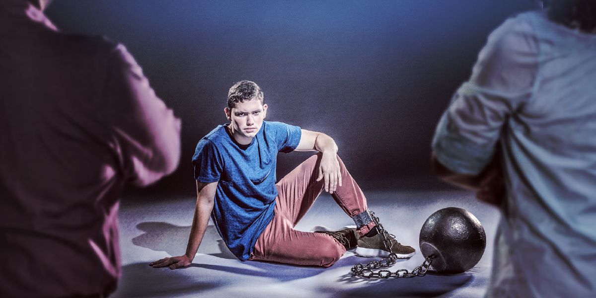 A teenage boy has a ball and chain attached to his ankle