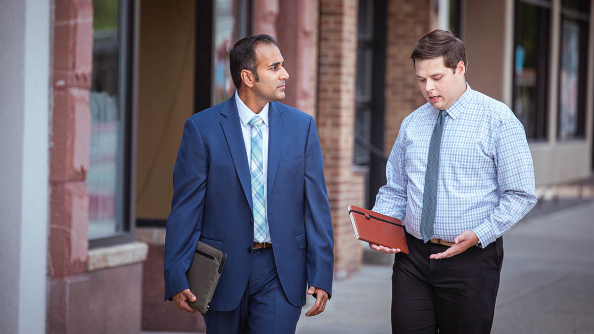 An elder listening intently to a brother express himself as they work together in the field ministry.