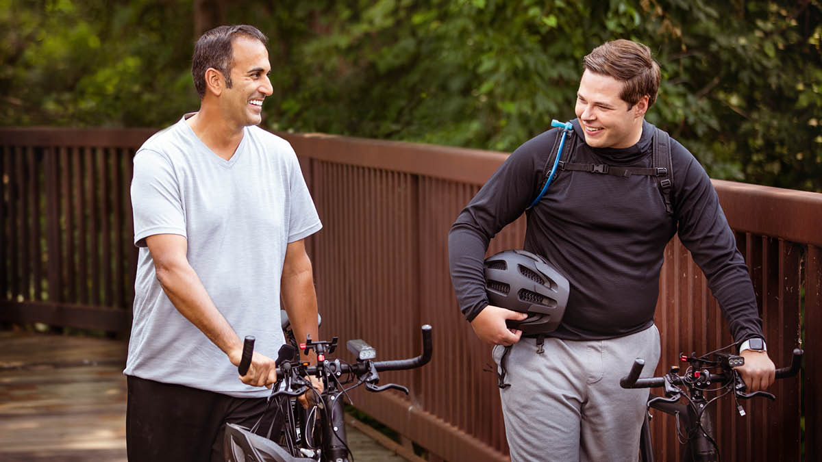 The elder and the brother smiling and enjoying themselves as they get ready to go for a bike ride.