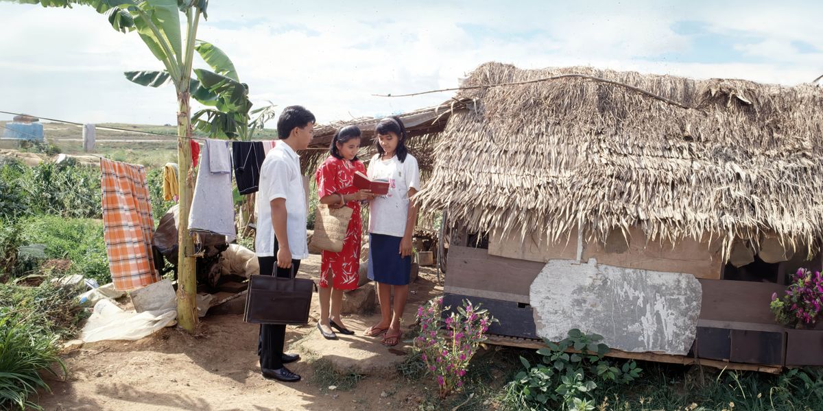 A couple in the Philippines, witnessing to a woman outside her modest home.