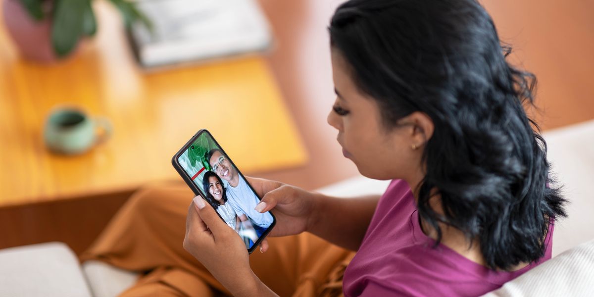 A young woman looking at a photo of herself with her boyfriend on a smartphone.