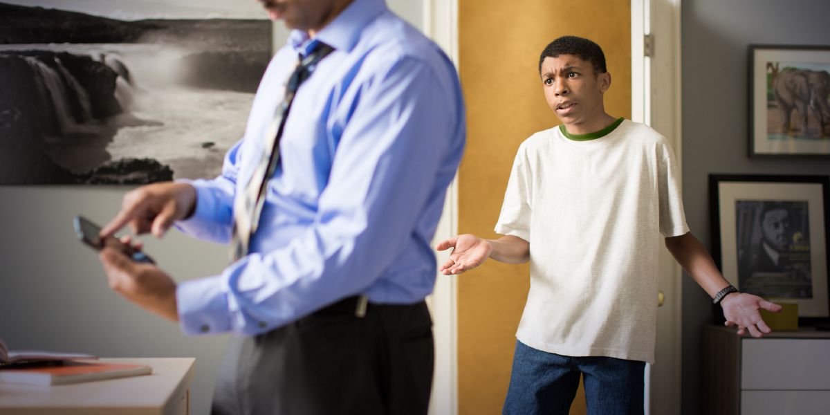 A father looks at his son’s phone, and the son is upset
