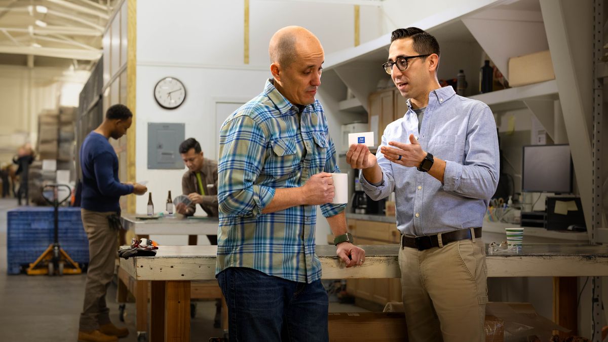 A brother handing a jw.org contact card to a workmate while they take a break.
