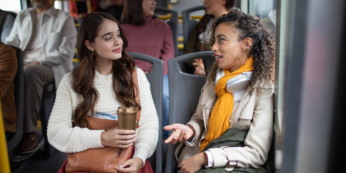 One of Jehovah’s Witnesses listening attentively to a woman as she expresses herself while they ride public transportation.