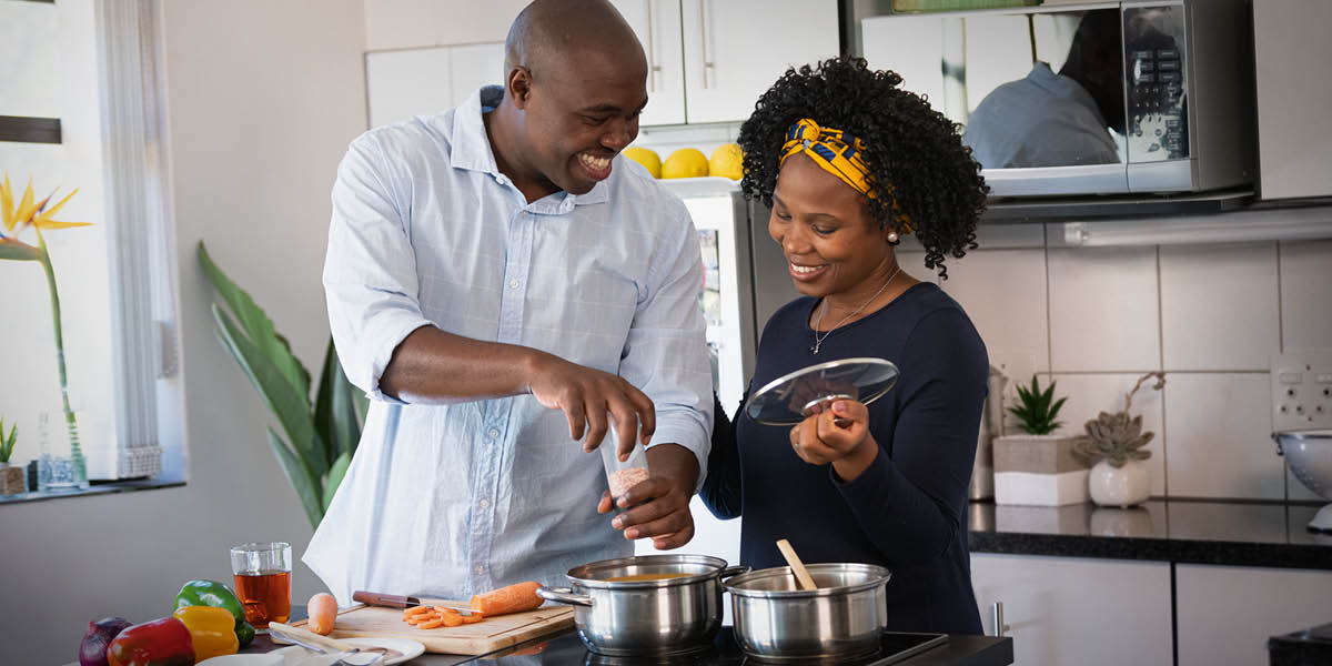 A husband and wife happily preparing a meal together.