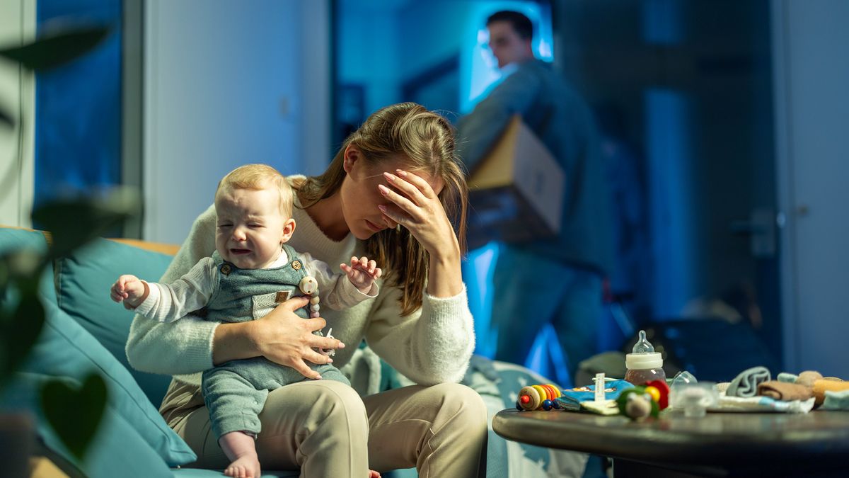 The woman shown earlier now holding a crying baby and sitting with her head in her hand. The man is moving out with a box of his personal belongings.