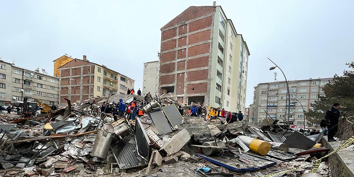 Rescue workers assembling together on a mound of rubble from a collapsed building.