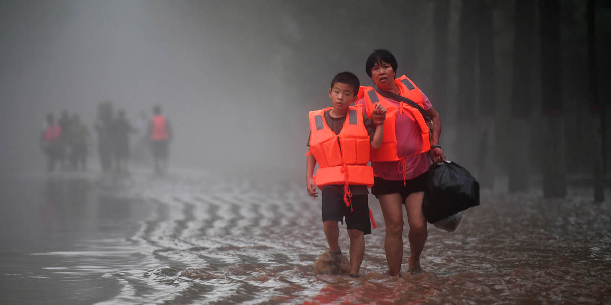 A woman and a child standing on a flooded roadway.